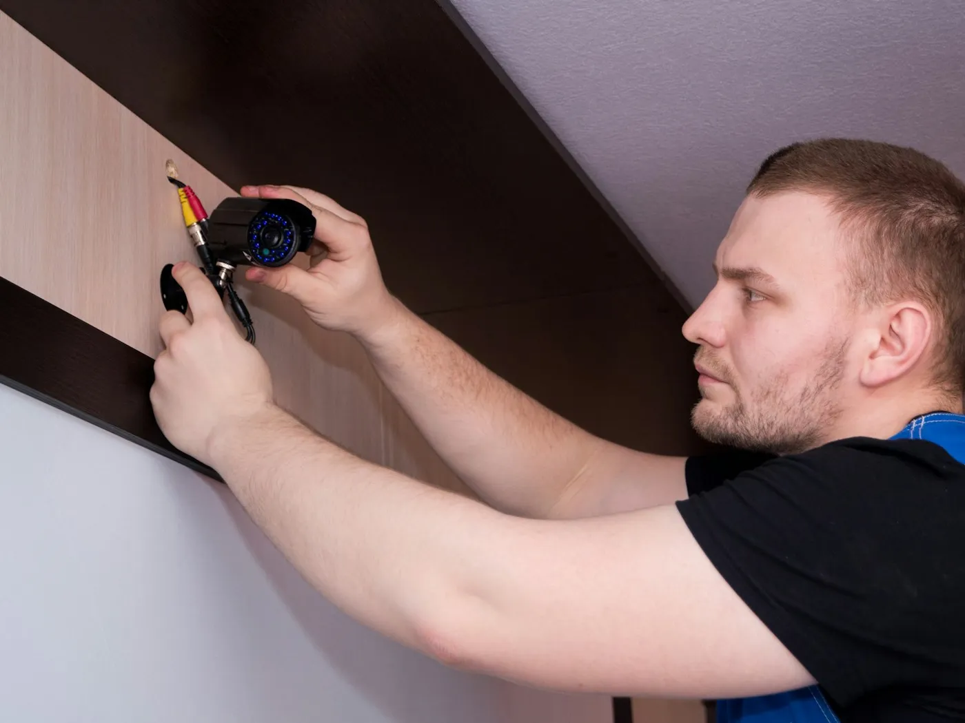 A technician mounting and wiring a CCTV camera