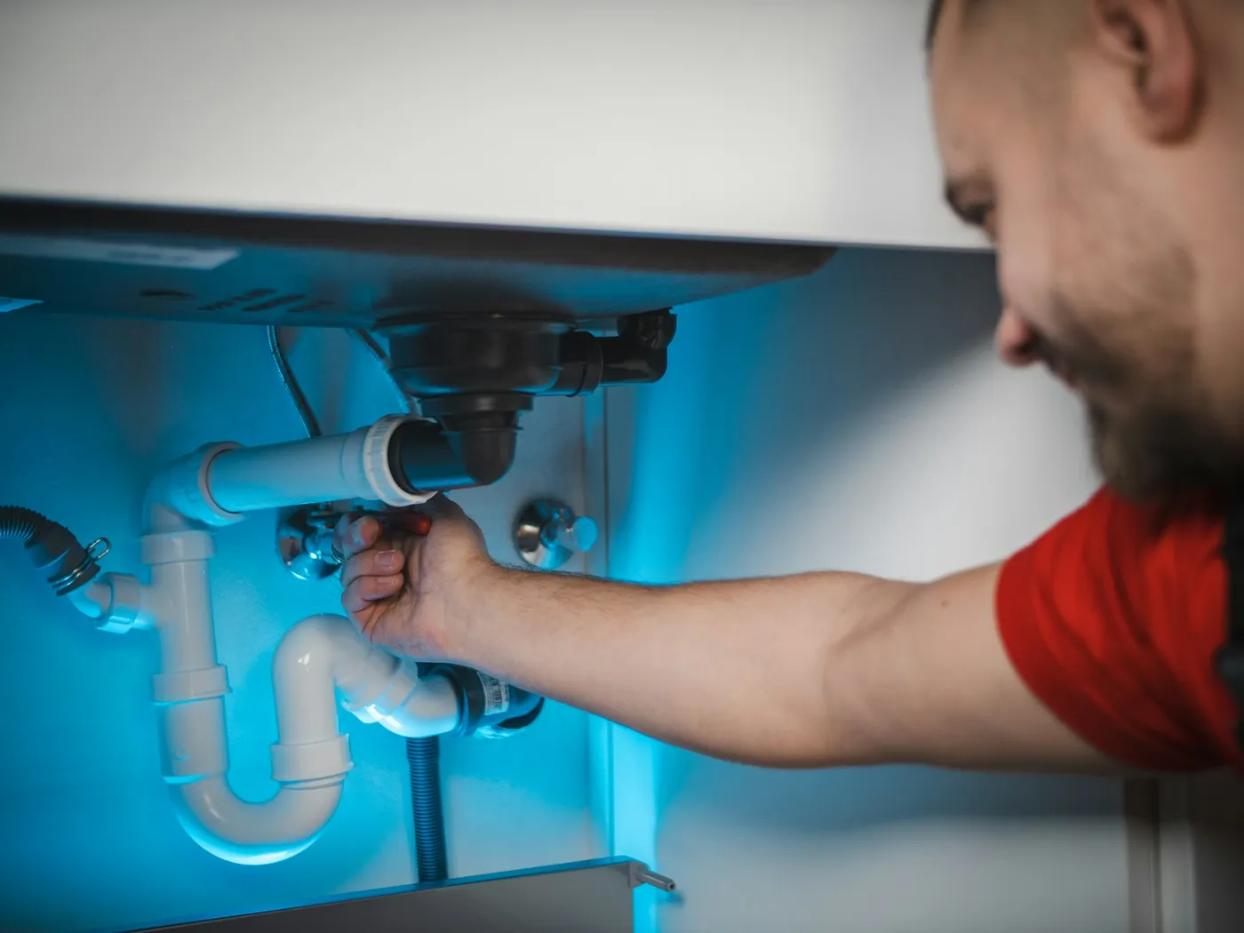 A plumber fixing the waste pipe under a sink